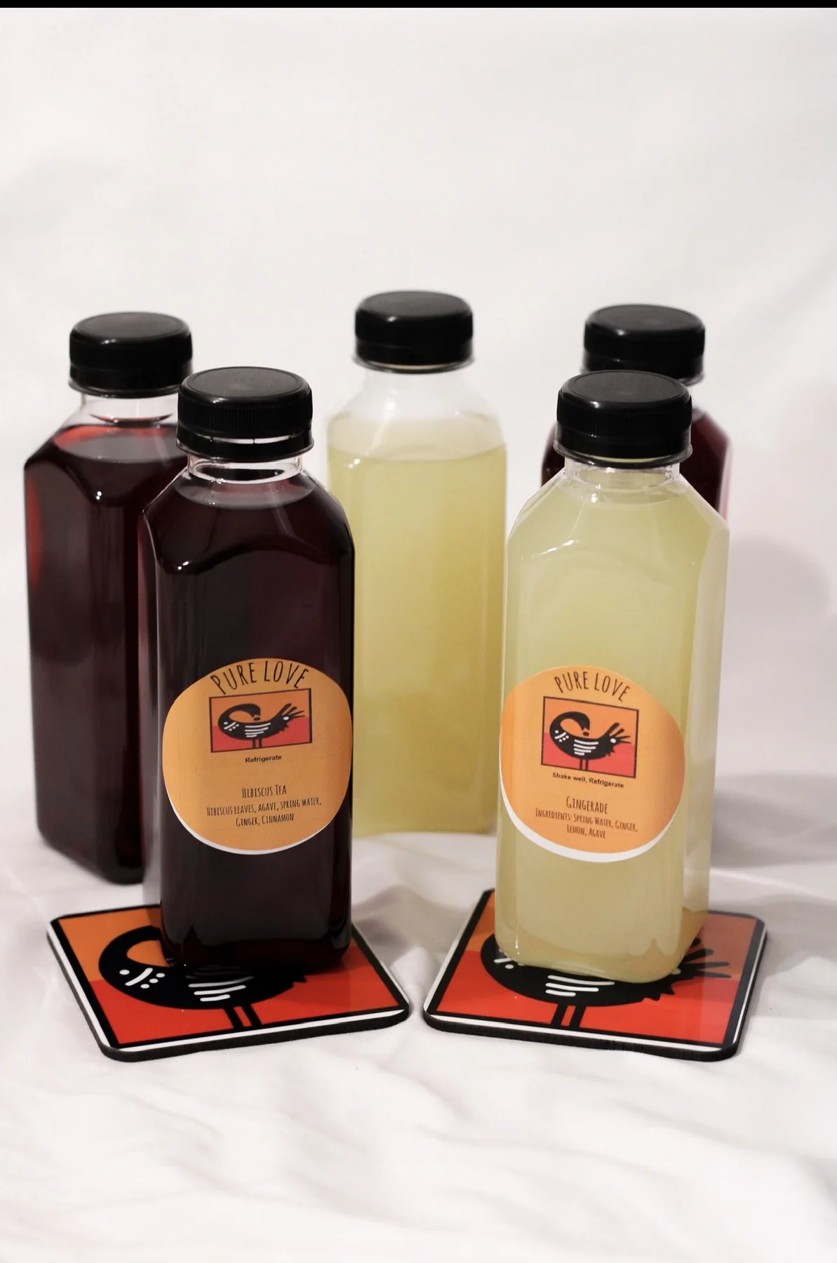 Bottled hibiscus tea and gingerade displayed on branded coasters