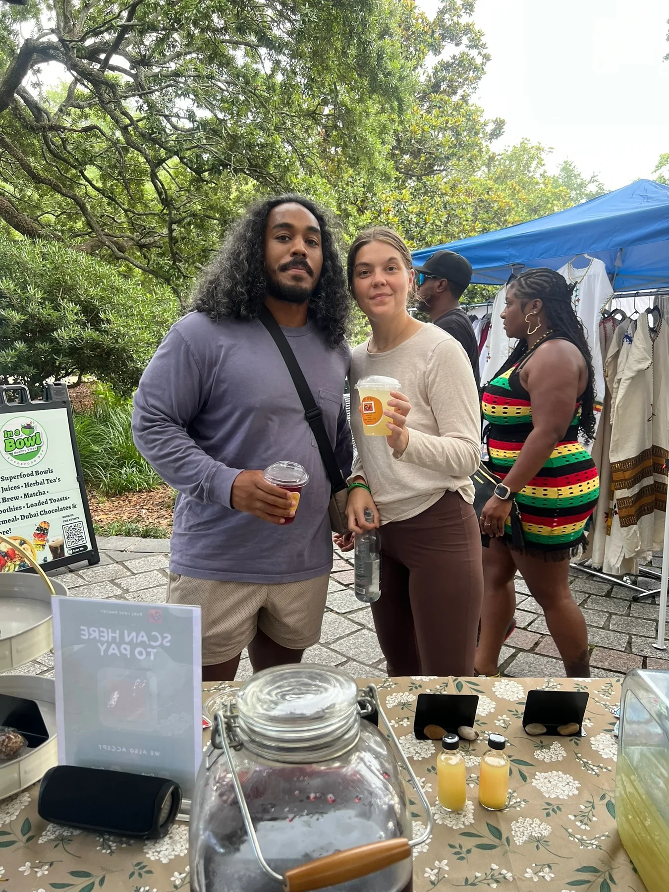 Two guests enjoying Pure Love Pantry drinks at an outdoor market