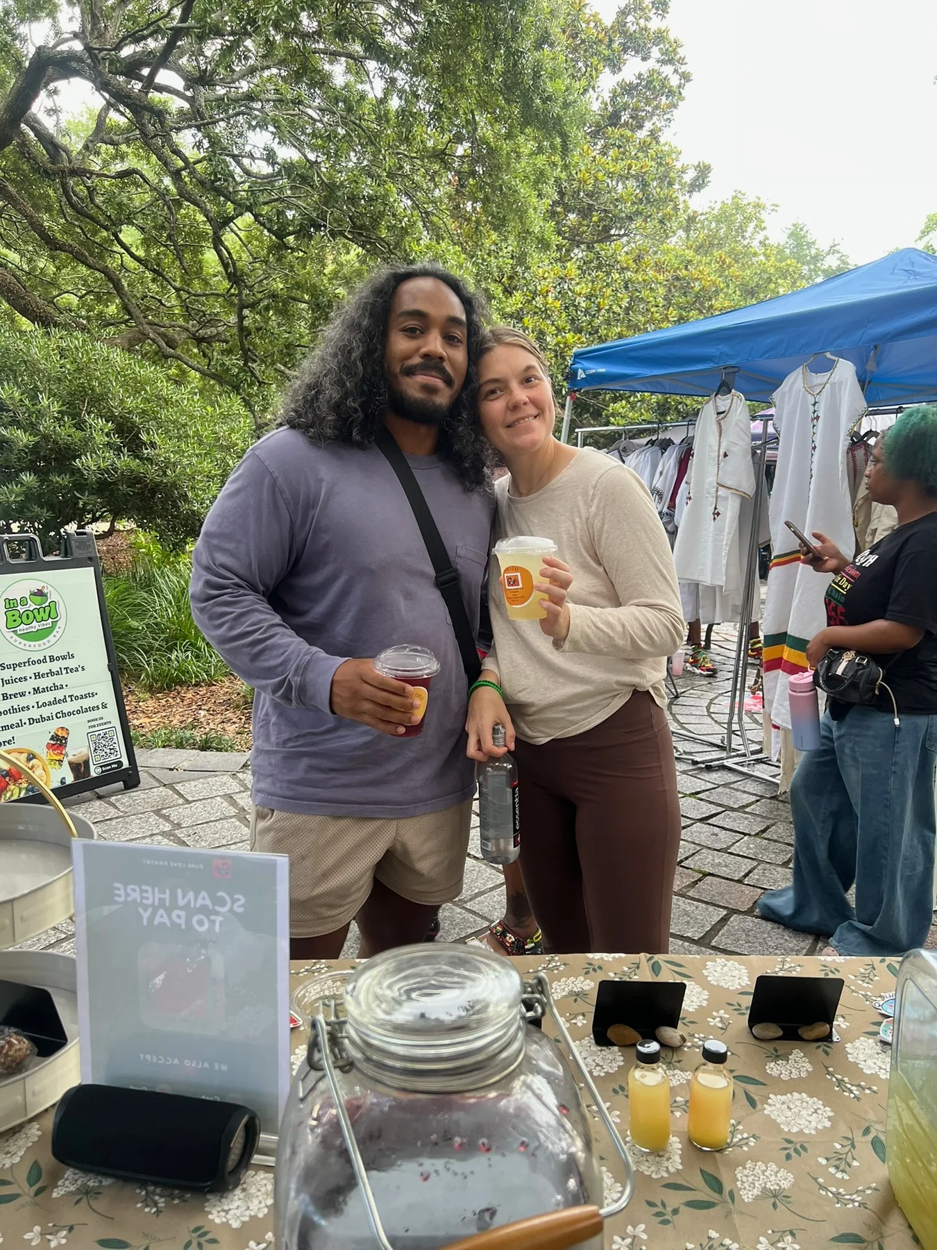 A couple sharing Pure Love Pantry beverages at a market
