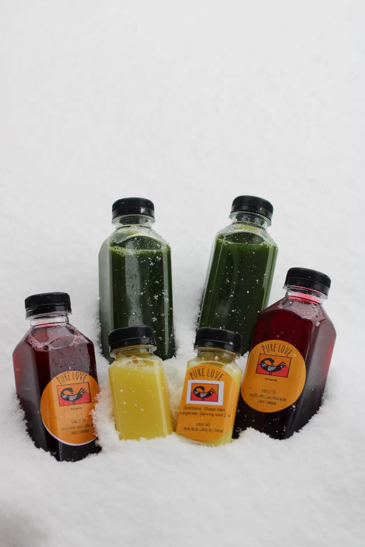 Pure Love Pantry juices and wellness shots displayed in snow